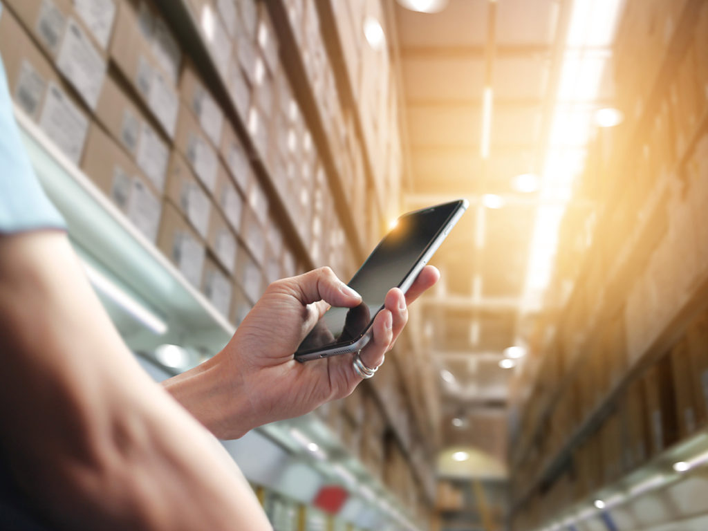 Person in warehouse using cellphone to automate processes
