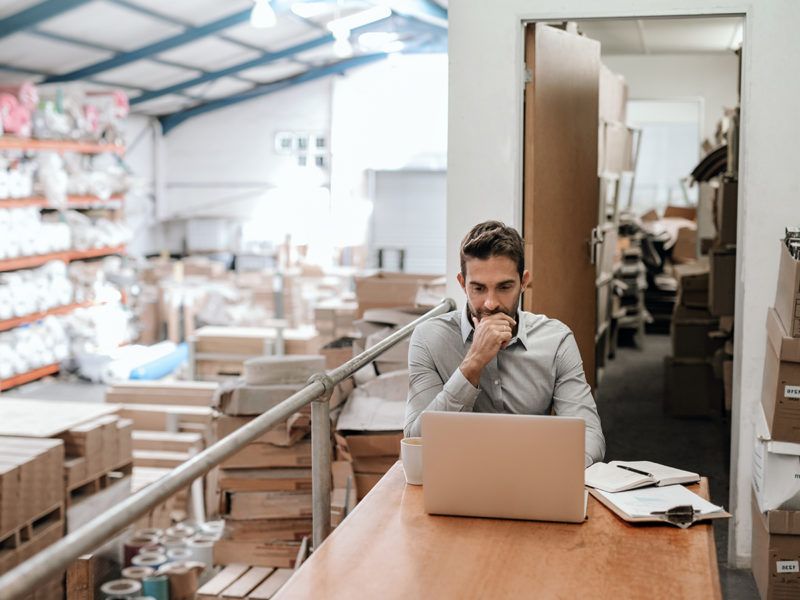 Manager working online while sitting in a warehouse office