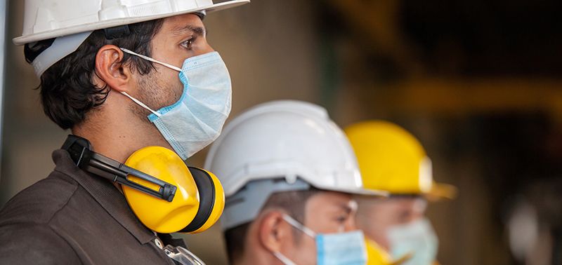 Workers wear protective face masks for safety in machine industrial factory.
