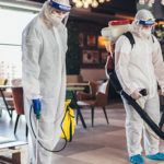 Professional workers in hazmat suits disinfecting indoor of cafe or restaurant, pandemic health risk, coronavirus