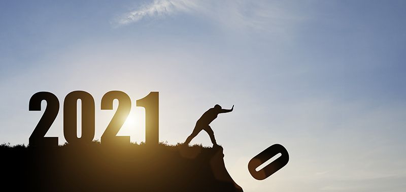 Man push number zero down the cliff where has the number 2021 with blue sky and sunrise. It is symbol of starting and welcome happy new year 2021.
