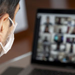 Man using a mask and having a video conference with work team am