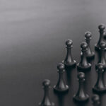 3D illustration of many pawns over black background plus a golden one. Concept of talent sourcing and spotted candidate