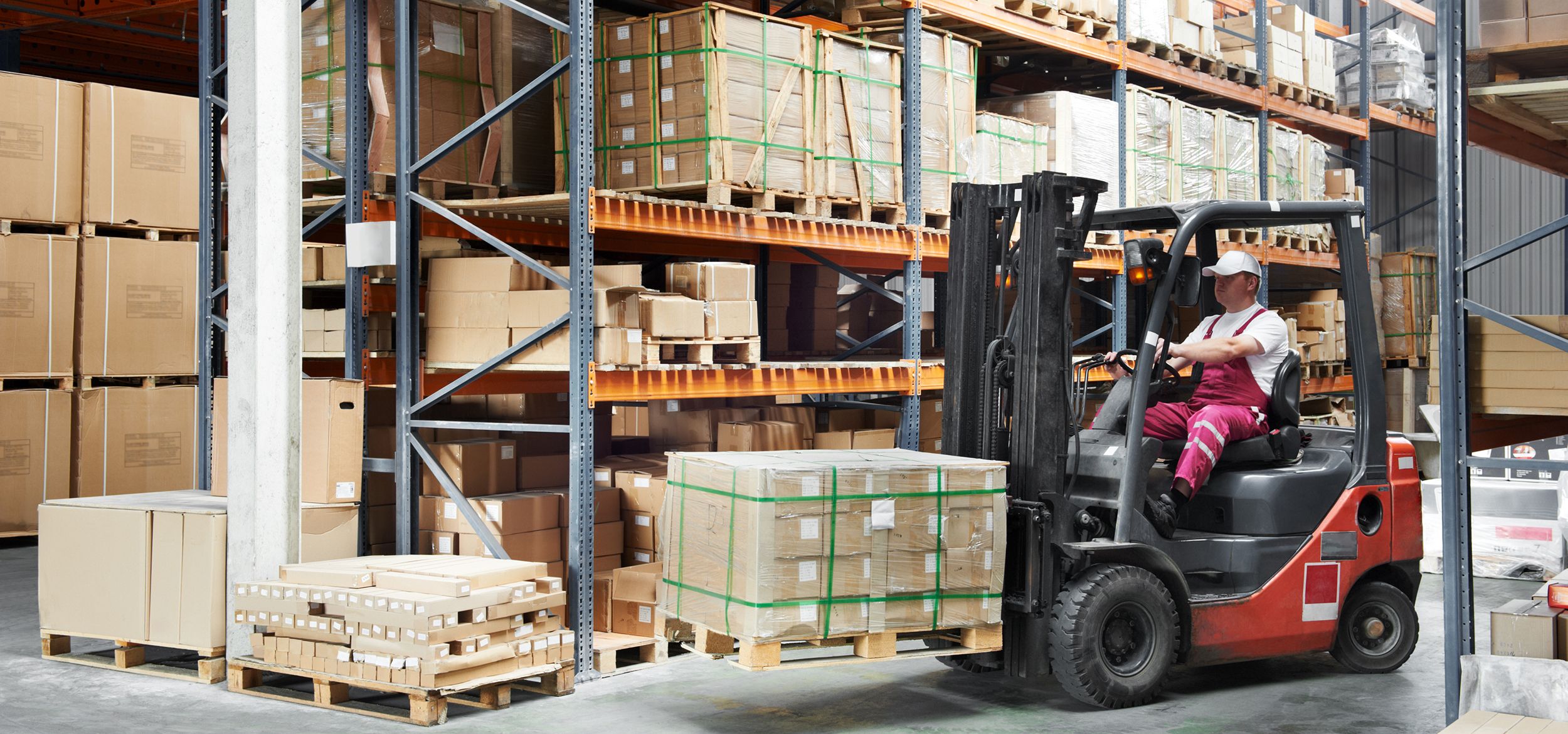 warehouse worker driver in uniform delivery and loading cardboxes by forklift stacker loader