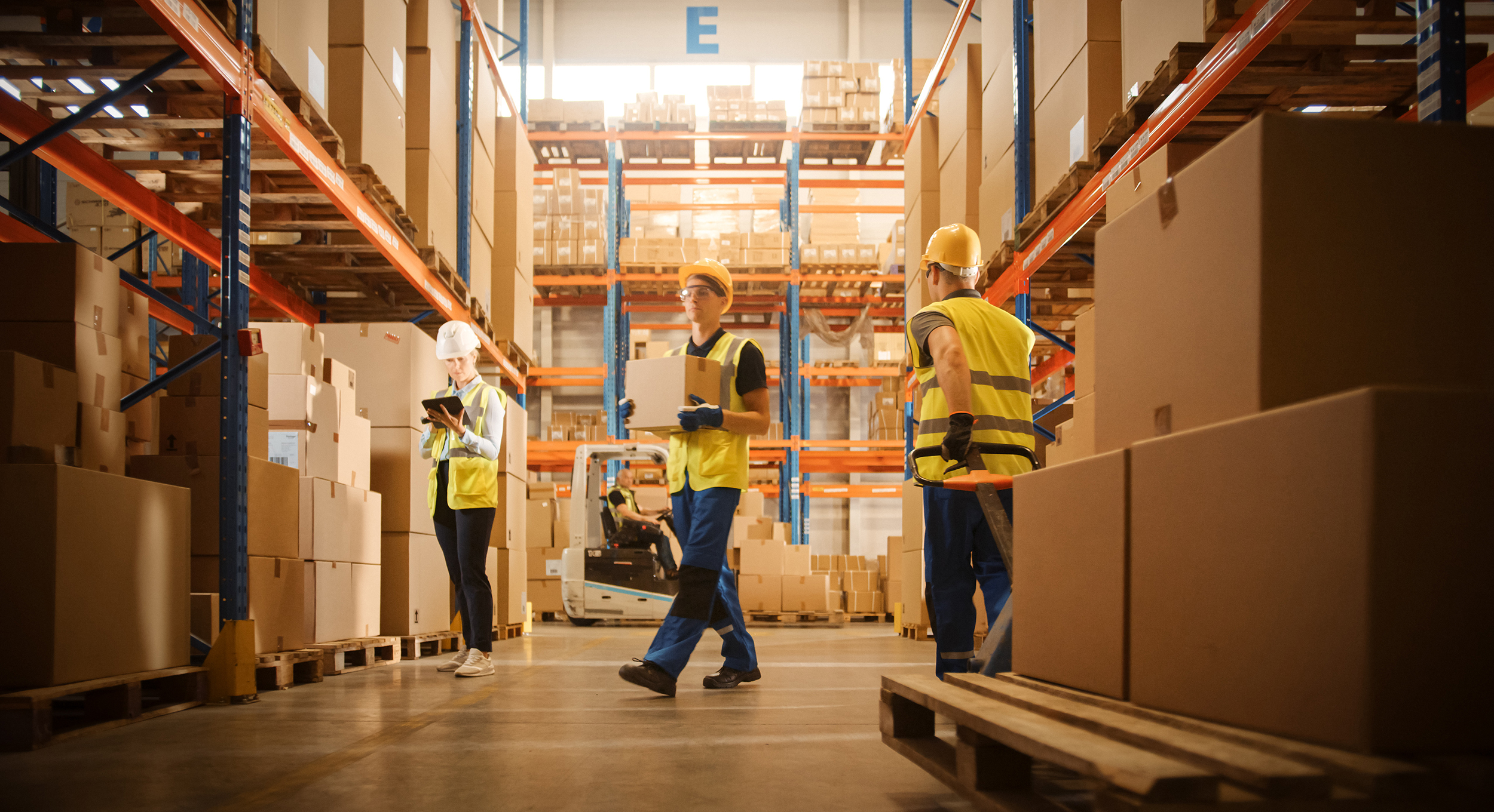 Retail Warehouse full of Shelves with Goods in Cardboard Boxes, Workers Scan and Sort Packages, Move Inventory with Pallet Trucks and Forklifts. Product Distribution Logistics Center.