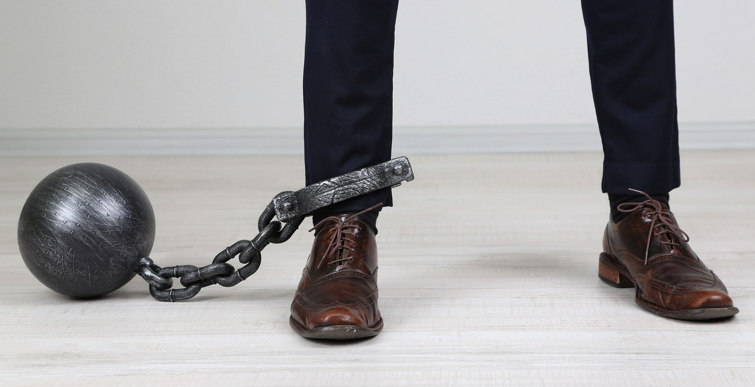 Business worker with ball and chain attached to foot