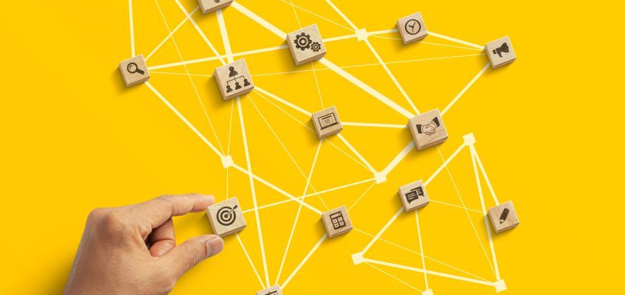 Business strategy to success, business management or start up business concept. Hand is arranging wooden blocks with business icon in low polygon rocket shape network on yellow background.