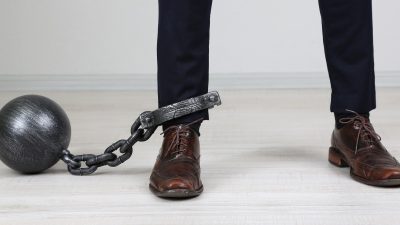 Business worker with ball and chain attached to foot