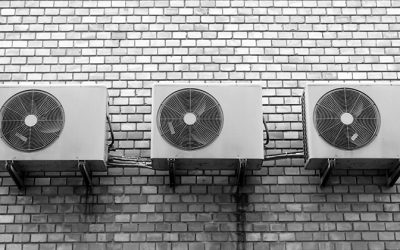 three air conditioning units on a white brick wall