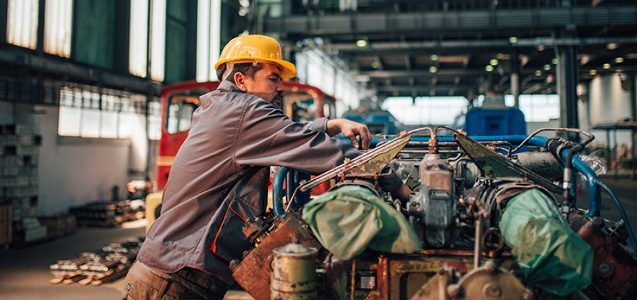 Train mechanic working on engine at heavy industry factory.